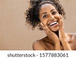 Beautiful young woman smiling after fantastic face treatment. Happy beauty african girl excited after spa treatment isolated on background with copy space. Surpise and astonishment beauty concept.