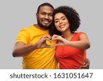 love, valentines day and people concept - happy african american couple making hand heart gesture over grey background