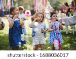 Small children outdoors in garden in summer, playing with bubbles.