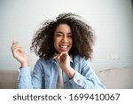 Cheerful african teenage girl blogger talking to camera recording vlog. Happy mixed race young woman laughing making video call at home. Funny social media influencer streaming blog. Webcam view.