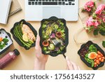 Female hands hold food delivery box having lunch at work from home office. Business woman worker eats salad take away nutrition daily healthy meal weight loss diet menu at workplace flat lay top view.