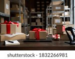 Table with laptop and gift boxes with sale tags on table in warehouse. Online ecommerce retail business black friday discounts deals, free shipping. Best buy holiday offers concept storage background.