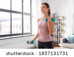 fitness, sport and healthy lifestyle concept - smiling young woman with dumbbells exercising at home