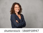 Confident young woman wearing eyeglasses and standing on gray wall. Portrait of smiling businesswoman isolated against grey background with copy space. Proud student girl with specs looking at camera.