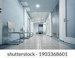 Empty modern hospital corridor, clinic hallway interior background with white chairs for patients waiting for doctor visit. Contemporary waiting room in medical office. Healthcare services concept