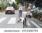 Scared girl with phone and headphones runs away from the car at a pedestrian crossing
