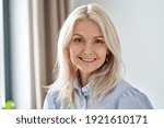 Smiling sophisticated 50s middle aged blond business woman looking at camera. Happy mature elegant old lady professional businesswoman posing at home office. Headshot close up portrait