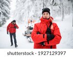 Woman paramedic from mountain rescue service outdoors in winter in forest, looking at camera.