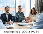 Happy businessman and businesswoman shaking hands at group board meeting. Professional business executive leaders making handshake agreement successful company trade partnership handshake concept.