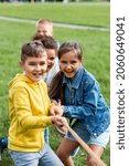 Small photo of childhood, leisure and people concept - group of happy kids playing tug-of-war game and running at park