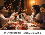 Small photo of holidays, party and celebration concept - multiethnic group of happy friends having christmas dinner at home