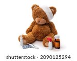 medicine, healthcare and childhood concept - teddy bear toy with bandaged head thermometer and drugs on white background