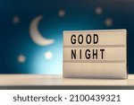 Small photo of sleeping and bedtime concept - close up of customizable light box with good night words over moon and night stars on blue background
