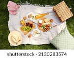 leisure and eating concept - close up of food, drinks and picnic basket on blanket on grass at summer park