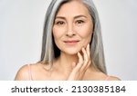 Small photo of Closeup portrait of gorgeous happy middle aged mature asian woman, senior older 50 year lady looking at camera touching her face isolated on white. Ads of lifting anti wrinkle skin care treatment.