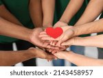 Small photo of charity, support and volunteering concept - close up of volunteers's hands holding red heart at distribution or refugee assistance center