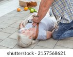 Small photo of Man performs a heart massage on an senior lady who fainted on the street