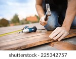 Handyman installing wooden flooring in patio, working with hammer