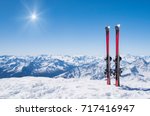 Pair of skis in snow with copy space. Red skis standing in snow with winter mountains in background. Winter holiday vacation and skiing concept. 