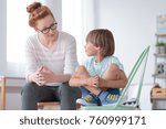 Young female school psychologist having serious conversation with smart little boy at her office