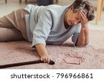 Sick senior woman with headache lying on the floor after falling down