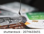 Small photo of Fishing hook is hooked on plastic bank credit card. Bank scammers concept