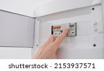 Small photo of Man turns on toggle switch with hand. Turn on light and supply electricity from the electrical panel concept