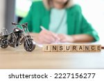 Motorcycle, travel and medical insurance concept. Motorcycle model and word insurance on table, blurred manager with documents in background.