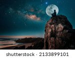 Small photo of person silhouette sitting on the top of the mountain meditating or contemplating the starry night with Milky Way and Moon background