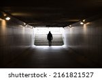 Small photo of Man walking in dark underground tunnel. Stranger anonymous person. Unknown person in subway. Horror and thriller concept. Light at end of tunnel.