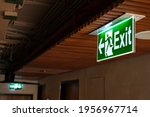 Green fire escape sign hang on hotel ceiling. Green exit sign. LED green Emergency exit sign in the ceiling of modern hotel building.