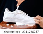Woman cleaning white leather shoes with cleaning foam. The concept of caring for leather footwear