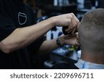 Small photo of Professional Master barber shaves the client's beard with a electric trimmer. Haircut of a man's beard in a barber shop. Barber Men. Advertising and barber shop concept.