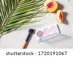 Small photo of Vacation. A sculpting palette and a blush brush lie on the beach sand, surrounded by vibrant fruits, corals, and palm leaves. Close-up, top view, desktop wallpaper. Copyspace.ation.