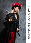 Small photo of A pretentious Gothic lady in a long leather coat and a hat with roses, uses a cane.