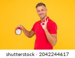 Small photo of All right. Happy man hold alarm clock showing OK sign. Punctuality and accurate timekeeping. Chronometry and timekeeping. Clock gives the right time