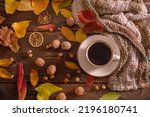 Autumn, fall leaves, hot cup of coffee and warm scarf on wooden table background, top view, copy space. Seasonal, morning coffee, sunday rest and still life concept.