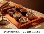 Herbal medicine concept with bowls of dried chopper herbs and spices on the wooden tray.

