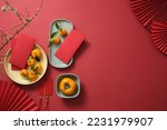 Fruits, lucky money, paper fan, and Lucky envelopes on a red background. Empty space for text. Chinese lunar new year. Top view