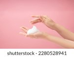 A beautiful woman hands with white foam mousse placed on over a pink background. Cosmetic product promotion