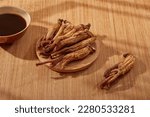 Small photo of Red ginseng displayed on wooden dish with a bowl of medicine. Red ginseng (Panax ginseng) helps strengthen the body's immune function, support the symptoms of fatigue and body weakness