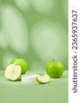 Small photo of Round-shaped podium in white color is displayed on pastel background with green apple. Blank space on the podium for product presentation of Green Apple (Malus domestica) extract