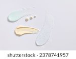 Small photo of Different cosmetic textures of face cream, serum and exfoliating cream on white background. Cosmetics induce a smoother feel and appearance to the skin. Scene for advertising.