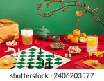 Small photo of A seahorse chess board, a glass of soft drink, a plate of tangerines, a plate of sunflower seeds, a plate of colorful gummy candy, a tea set, etc. are displayed on a red and green background.