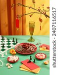 Small photo of Close-up of a plate of ginger jam, a plate of colorful gummy candy, a plate of nuts, a chess set and lucky money envelopes displayed on a green table. Tet tea table concept.