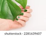 Female hand with vacation nail design. Glitter green nail polish manicure with rhinestone flower nail art. Female model hand with perfect green manicure on white background. Copy space. Place for text