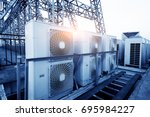 Air conditioner units (HVAC) on a roof of industrial building with blue sky and clouds in the background.