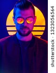 Small photo of Retro wave synth wave portrait of a young man in sunglasses. 80s sci-fi futuristic fashion poster style violet neon.
