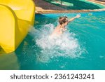 happy child slides down the yellow water slide in the water park. a joyful 10 year old boy has fun in the water park, riding down the hill.