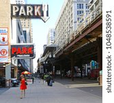 Small photo of Chicago, Illinois, USA - June 20, 2016: Street of Chicago with elevated railway. Some people walk on the sidewalk. Over the street runs the elevated railway.
